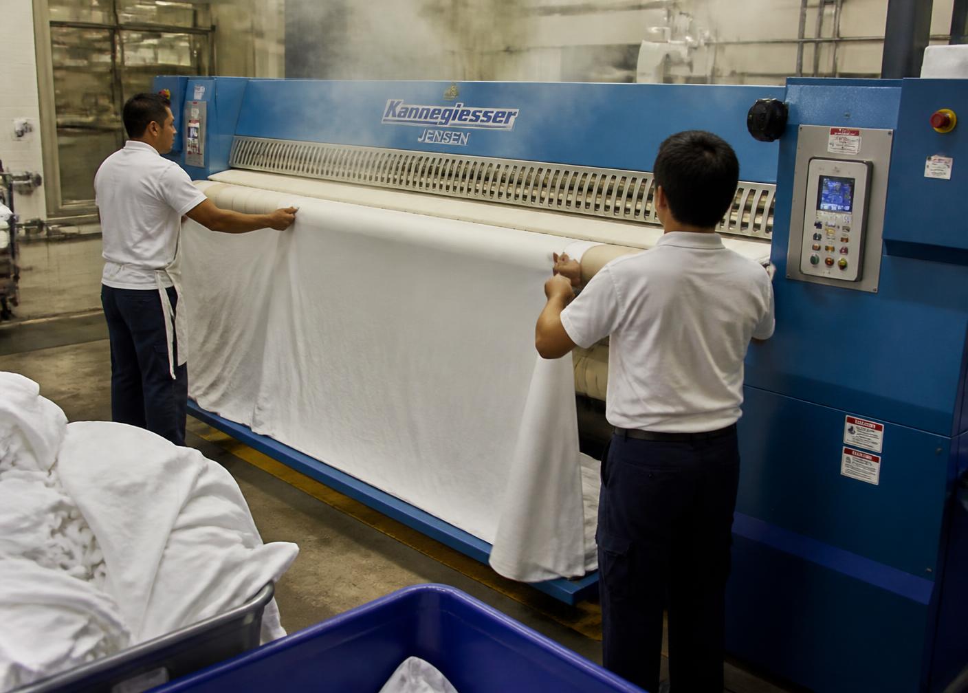 Công nhân đưa ga giường khách sạn vào máy là công nghiệp
